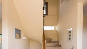 A staircase with beige steps and a wooden handrail, leading to an upper floor.