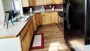 Una cucina con mobili in legno, un frigorifero nero, un lavello e un piano cottura.