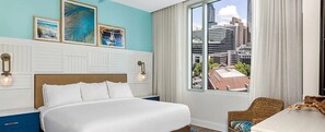 Camera d'albergo con un letto grande, vista sulla città e opere d'arte alle pareti.