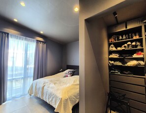 Quarto com cama, guarda-roupa e janela com cortinas.