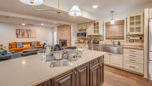 Une cuisine moderne dotée d’un grand îlot central, d’appareils électroménagers en acier inoxydable et d’un mur décoratif en briques.