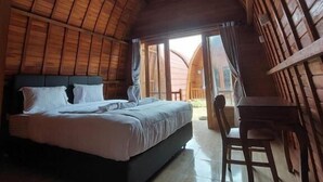 A room with a curved wooden ceiling, a bed with white bedding, a wooden table, and a chair. - les chalets pecatu (Pecatu)