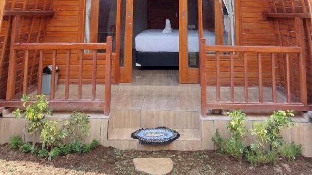 A wooden cabin with a pitched roof, a balcony, and a bed visible inside. - les chalets pecatu (Pecatu)