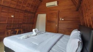 A cozy, wooden-paneled room with a bed, a chair, and a small table. - les chalets pecatu (Pecatu)