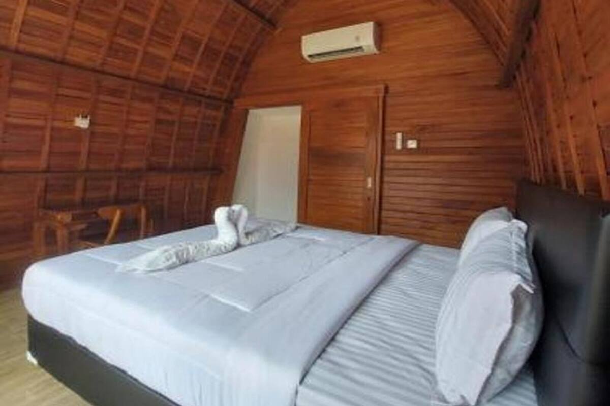 A cozy, wooden-paneled room with a bed, a chair, and a small table.