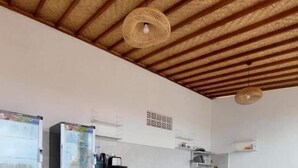 A kitchen with a white countertop, two refrigerators, gas cylinders, a white chair, and a woven ceiling light fixture. - les chalets pecatu (Pecatu)