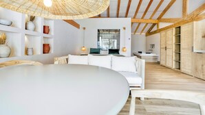 A modern interior with a white sofa, a round table, and a woven ceiling light fixture. - &Tales Villas Collection (Óbidos)