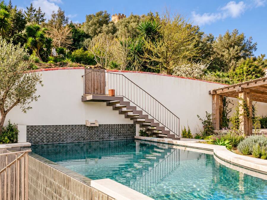 Una piscina con cubierta de madera, una escalera que lleva a un balcón y una vista de un castillo al fondo.