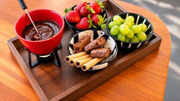A tray with a chocolate dipping bowl, strawberries, grapes, and chocolate-covered cookies.