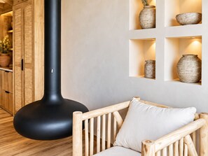 A modern interior with a black, cylindrical object, wooden furniture, and shelves with pottery. - &Tales Villas Collection (Óbidos)
