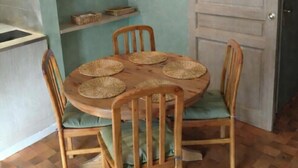 A dining area with a round wooden table, four chairs, woven placemats, and wicker baskets on shelves.
