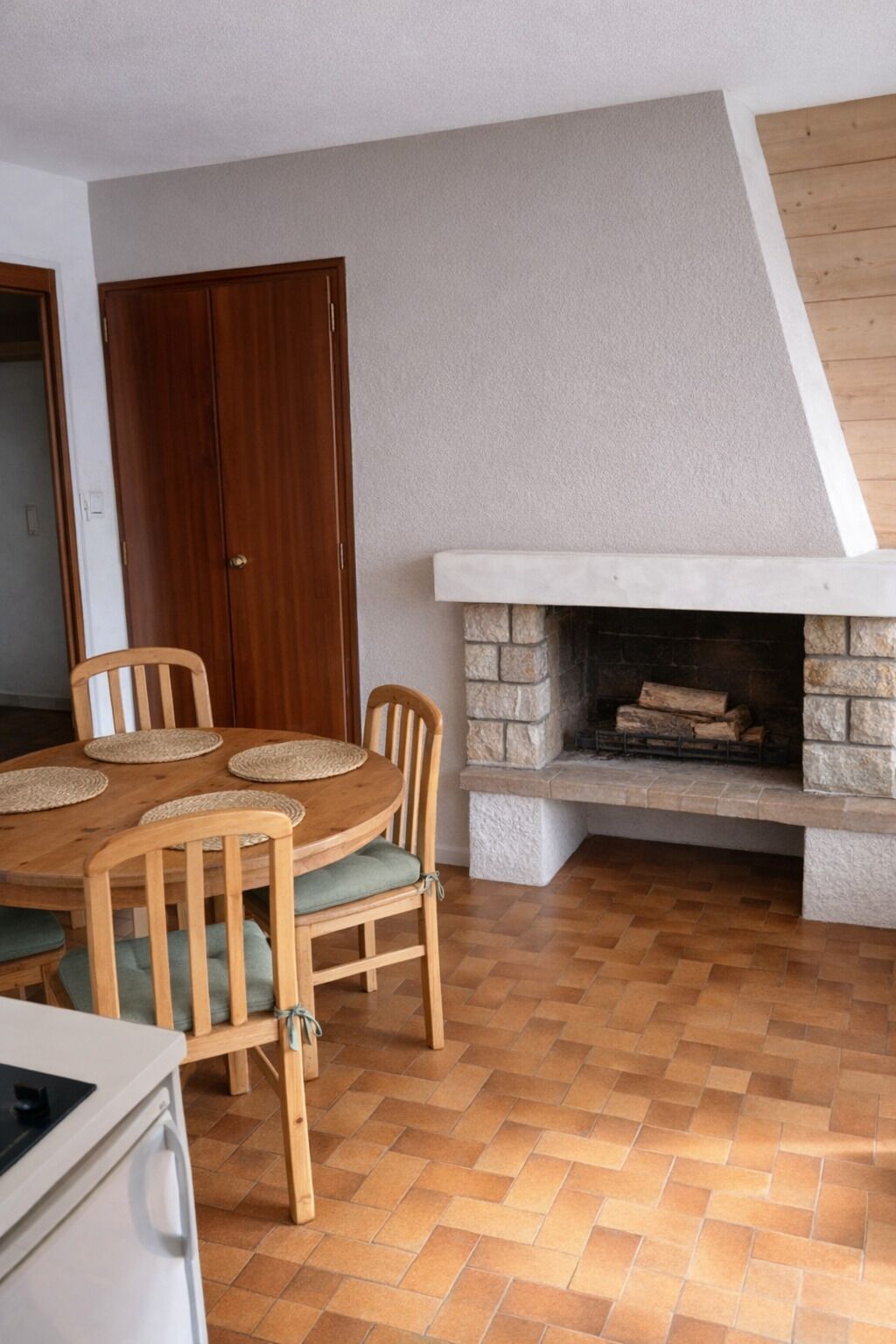 Ein Essbereich mit Holztisch und -stühlen, einem Steinkamin und einem Fischgrätparkett.