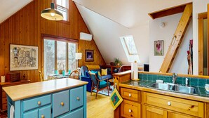 Un espace de vie de style loft comprenant une cuisine, un coin repas et une grande fenêtre.