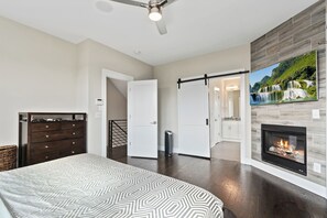 A bedroom with a bed, dresser, and a fireplace. - Modern Rooftop Oasis, Gym, EV Charger with Skyline Views in Uptown Charlotte (Charlotte)