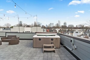 A rooftop terrace with a hot tub, outdoor seating, and a city skyline view. - Modern Rooftop Oasis, Gym, EV Charger with Skyline Views in Uptown Charlotte (Charlotte)