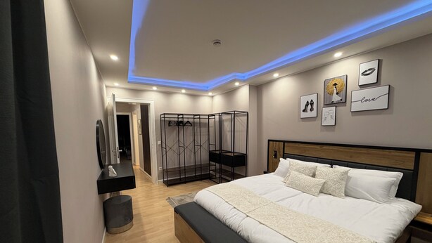 Une chambre à coucher moderne avec un grand lit, un dressing et une salle de bain avec un miroir.