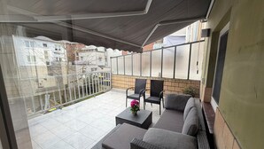 Un patio couvert avec un canapé, des fauteuils et une table.