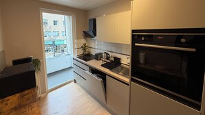 Une cuisine moderne équipée d’un four encastré, d’un évier et d’une fenêtre donnant sur la rue.