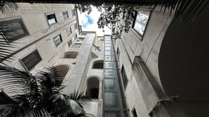 Une cour étroite à plusieurs niveaux, dotée d’ouvertures en arc de cercle et d’un puits d’ascenseur central en verre.