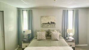 A bedroom with a bed, two nightstands, a ceiling light, a window with curtains, and a wall-mounted artwork. - Cozy 1-bedroom apartment in tranquil Huntington with AC (Huntington)