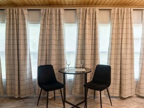 Una habitación con una mesa redonda, dos sillas y una ventana con cortinas.