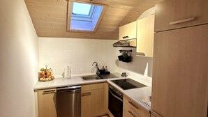 A compact kitchen with a skylight, a dishwasher, an oven, and a sink. - Vacation apartment in the Upper Bavarian Alps (Bad Kohlgrub)