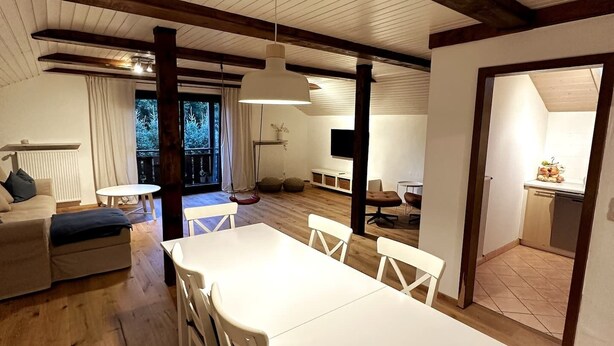 A spacious living area with a dining table, sofas, and a hanging light fixture. - Vacation apartment in the Upper Bavarian Alps (Bad Kohlgrub)