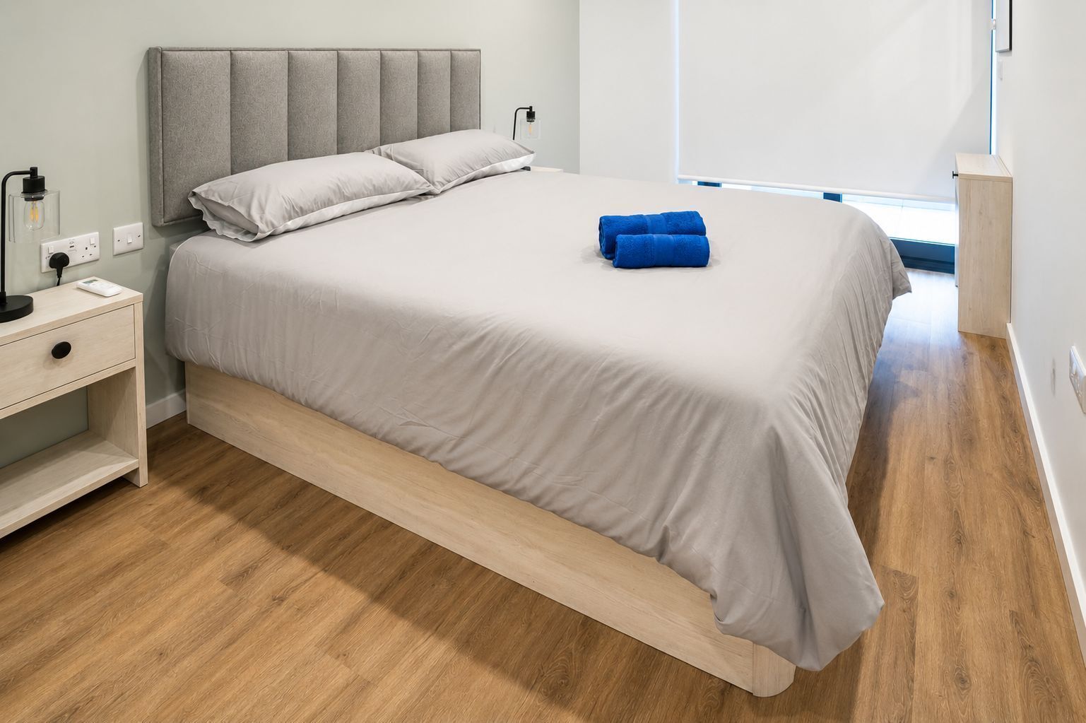 A modern bedroom with a bed, bedside table, and a nightstand.