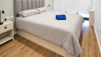 A modern bedroom with a bed, bedside table, and a nightstand.