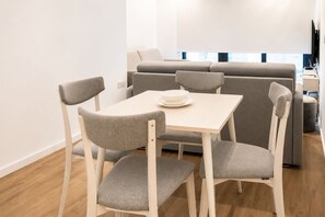 Een moderne woonkamer met een bank, een eettafel met vier stoelen en een televisie.