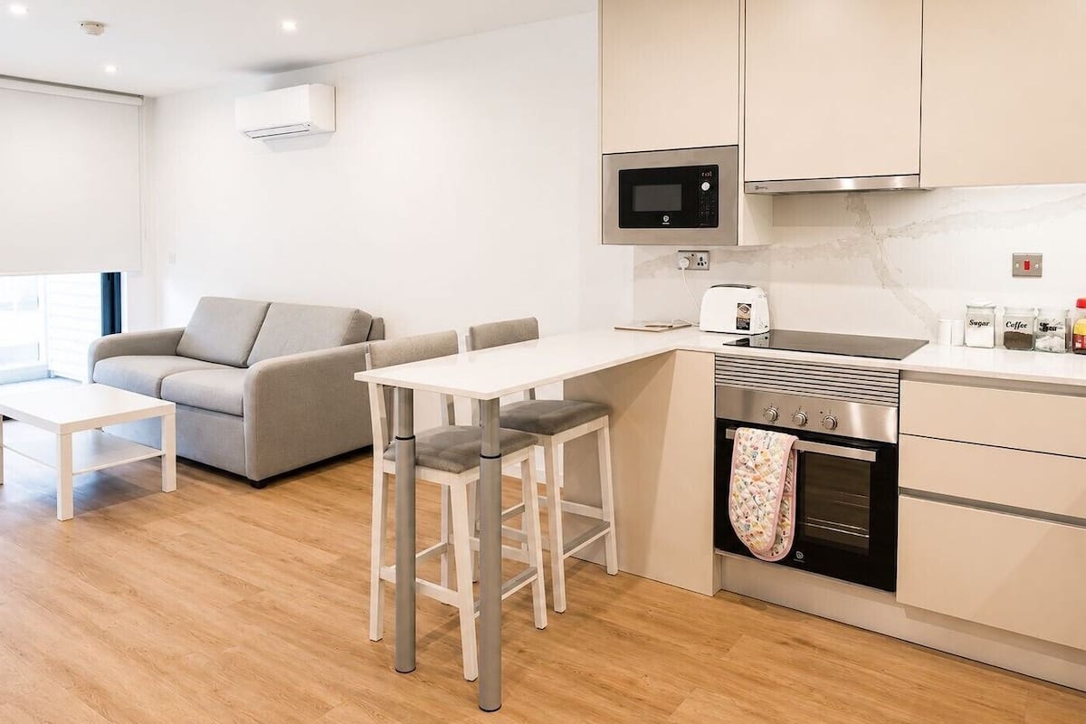 A modern kitchen with a microwave, toaster, oven, and cabinets. There is a dining area with a table and chairs.