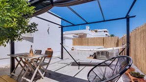 Um pátio com mesa, cadeiras, rede e plantas em vasos.