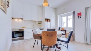 Uma cozinha moderna com armários brancos, forno embutido e uma área de jantar com mesa e cadeiras.
