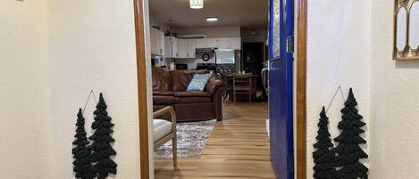 A hallway leading to a living room with a couch, a rug, and a welcome mat.