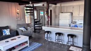 Una cocina moderna con una isla central, taburetes de bar y una escalera en espiral.