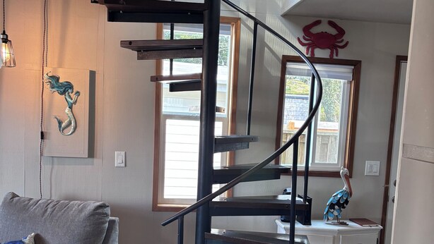 Una escalera en espiral con un armario blanco y una decoración de cangrejo en la pared.
