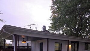 Un patio cubierto con mobiliario exterior, una parrilla y un hogar para fuego.