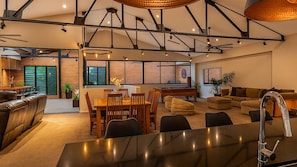 A spacious living area with a dining table, sofas, and a kitchen area with a pool table. - Newcastle CBD Penthouse (Newcastle West)