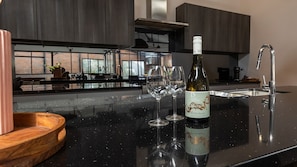 A modern kitchen with a wine bottle and glasses on the counter. - Newcastle CBD Penthouse (Newcastle West)