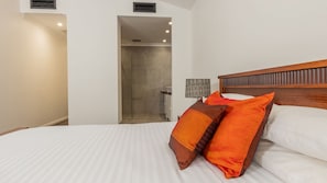 A hotel room with a bed, a nightstand, a lamp, and a shower area. - Newcastle CBD Penthouse (Newcastle West)