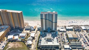 A high-rise hotel with a central atrium, parking lot, and beachfront view. - Seychelles 1207 (Panama City Beach)