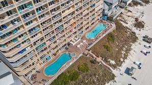 A high-rise hotel with multiple balconies, a central swimming pool, and a beach area. - Seychelles 1207 (Panama City Beach)