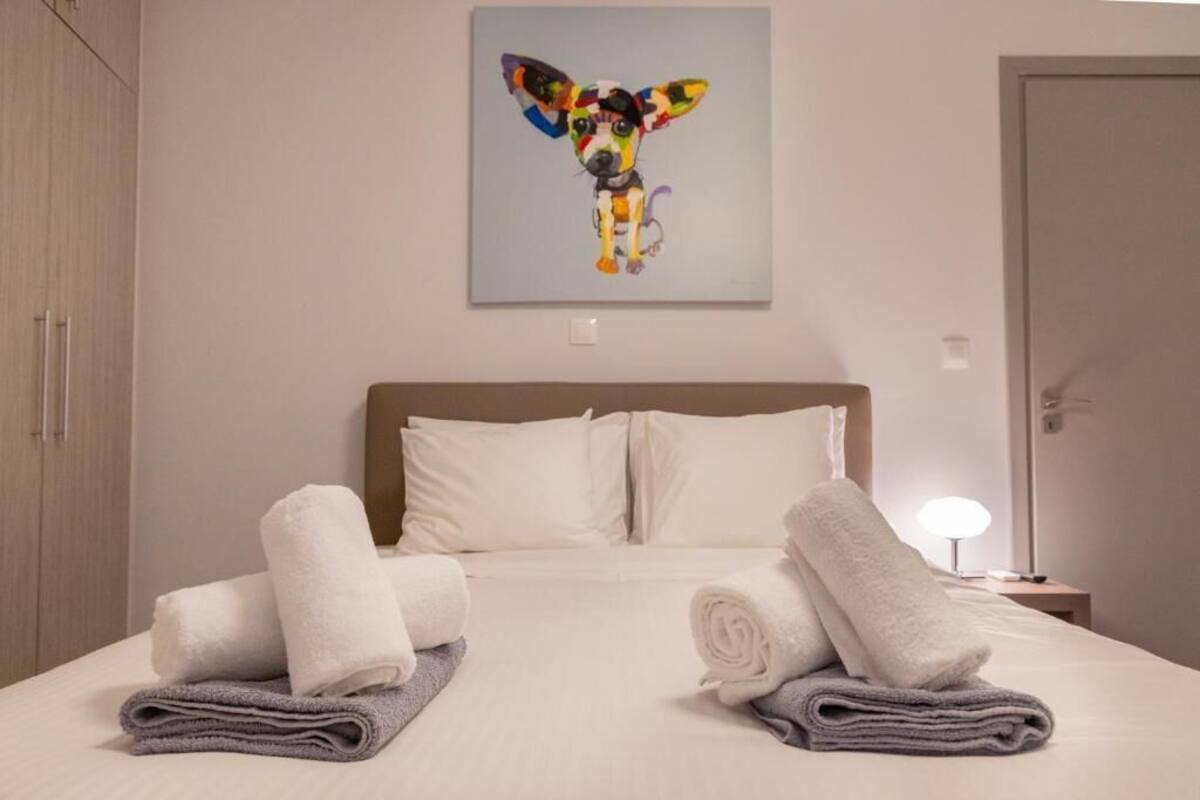 Una habitación de hotel con cama, almohadas, un cuadro y toallas.