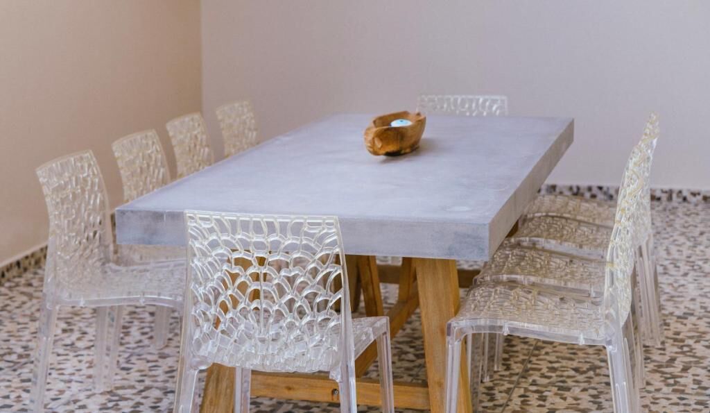 A rectangular table with a woven chair design, a wooden bowl, and a patterned floor.
