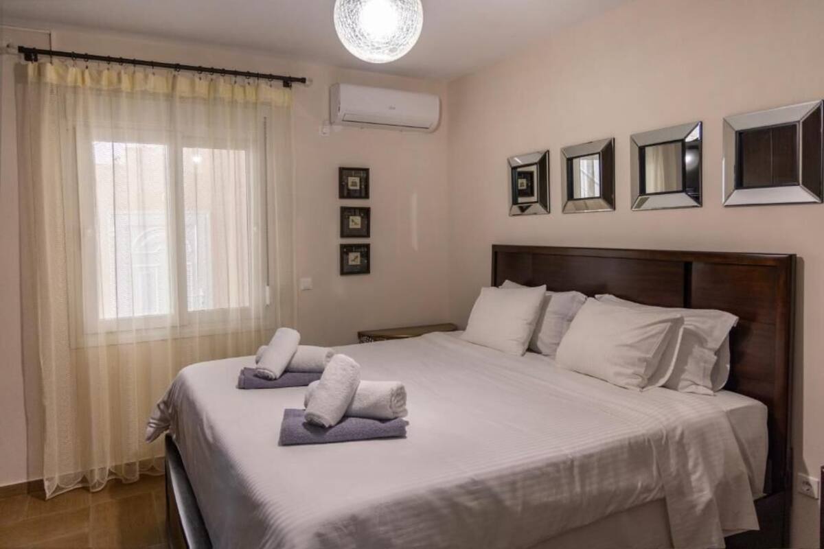 Habitación de hotel con una cama grande, una lámpara en el techo, aire acondicionado y varias fotografías enmarcadas en la pared.