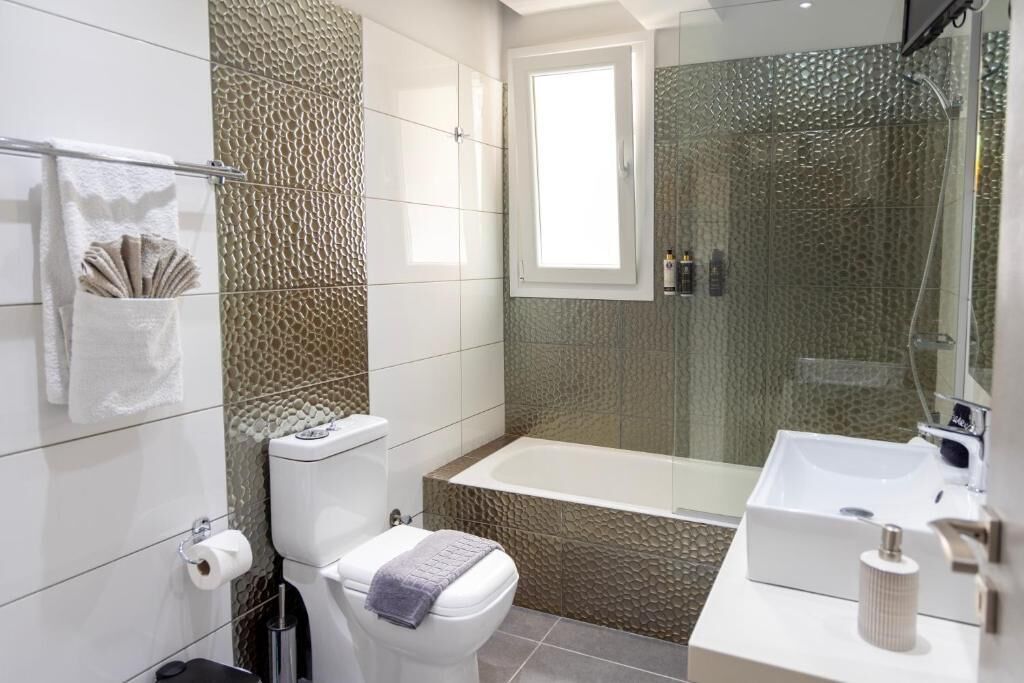 A modern bathroom with a toilet, bathtub, and sink.