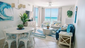 A modern living room with a dining area, a sofa, a coffee table, and a view of the ocean. - Stunning Remodeled Beachfront 3 BR | Wraparound Balcony | Private Beach Access (Orange Beach)