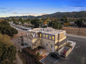 A multi-story building with a flat roof, a staircase, and a parking area with a 'No Parking' sign.