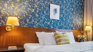 A hotel room with a bed, two bedside lamps, a framed picture, a nightstand, and a vase with flowers. - Penzion V Holi (Průhonice)