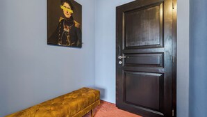 A room with a dark wooden door, a bench, and a portrait on the wall. - Penzion V Holi (Průhonice)